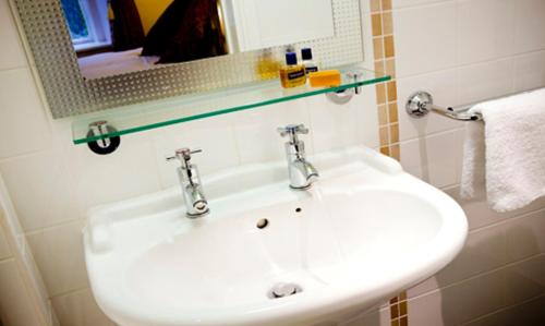 y baño con lavabo blanco y espejo. en The Junction Hotel, en Dorchester