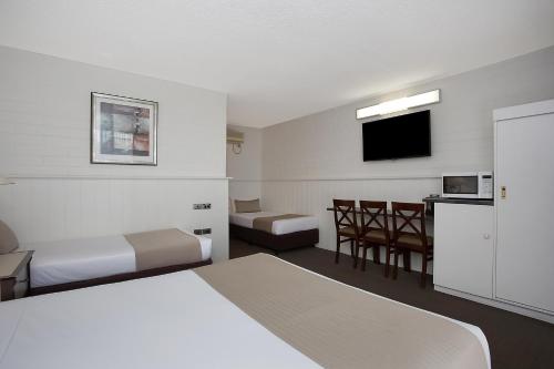a hotel room with two beds and a flat screen tv at Comfort Inn On Raglan in Warrnambool