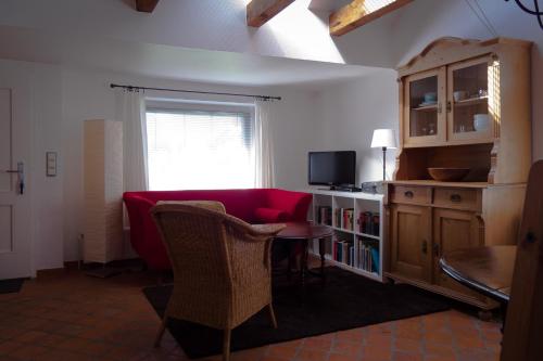 a living room with a red couch and a table at Lüttje Teihn in Pilsum