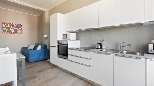 a kitchen with white cabinets and a blue couch at Italianway - Largo Allegri 4 in Milan