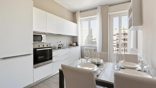 a white kitchen with a dining table and chairs at Italianway - Largo Allegri 4 in Milan