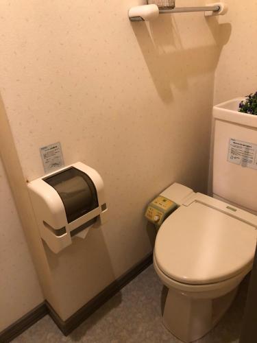 a bathroom with a toilet with a paper dispenser on the wall at Hotel Vegas (Adult Only) in Sapporo