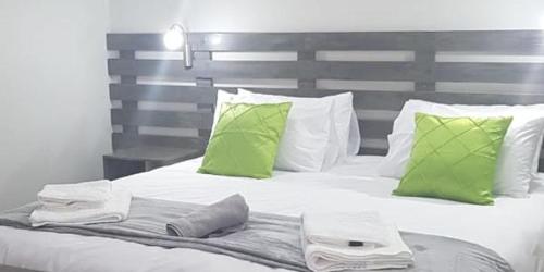 a bed with green and white pillows on it at George Executive Suites in George