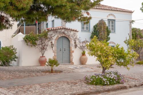 a white house with a blue door and trees at Mimoza in Spetses