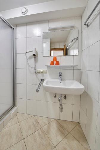 a white bathroom with a sink and a mirror at Ski & Bike Appartements Forsthaus in Saalbach Hinterglemm