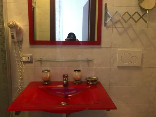 lavabo rojo en el baño con una persona que toma una foto en La Casa di Elena, en Roma