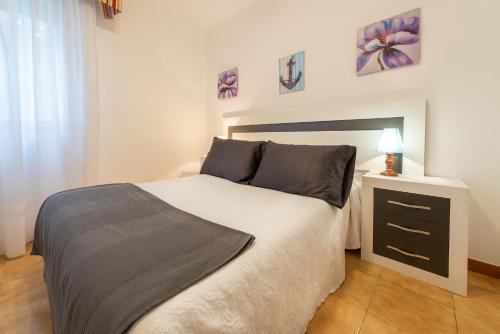 a bedroom with a large bed and a night stand at Hospedaxe Maria Aguiño in O Grove