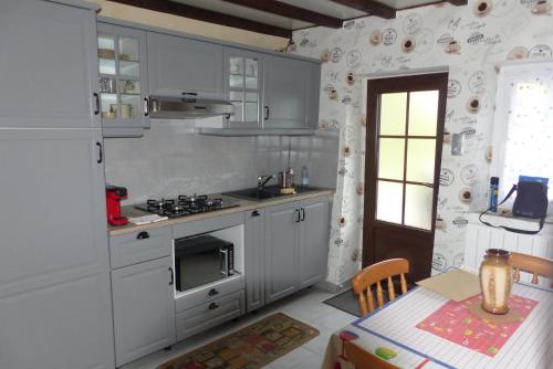 uma cozinha com armários brancos e uma mesa com uma mesa de sidx em Gîte rural Les Maires d'Avaux em Saint-Bresson