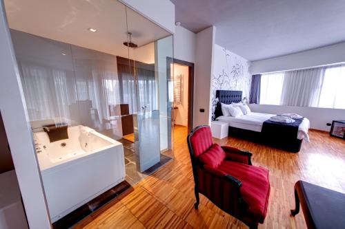 a bathroom with a tub and a bedroom with a bed at Sarroglia Hotel in Bucharest