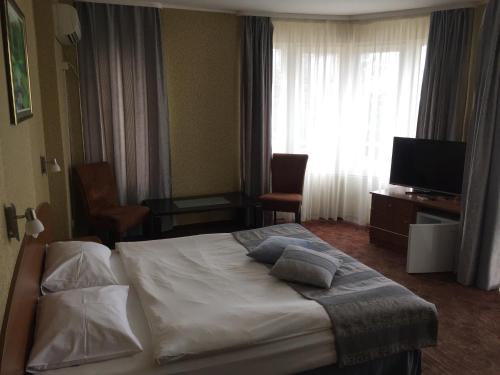 a hotel room with a bed and a television at Family Hotel Lazuren Briag in Burgas City