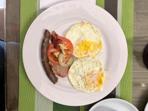 un plato de desayuno con huevos, salchichas y tomates en City Lodge Etosha, en Omuthiya