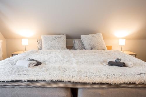 a bedroom with a large white bed with two towels on it at Penzion Bílá voda in Harrachov