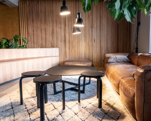 ein Wohnzimmer mit einem Sofa, einem Tisch und 2 Hockern in der Unterkunft Speicher7 Hotel in Mannheim