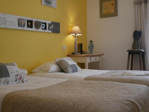 two beds in a room with yellow walls at Hotel Les Ambres in Roussillon