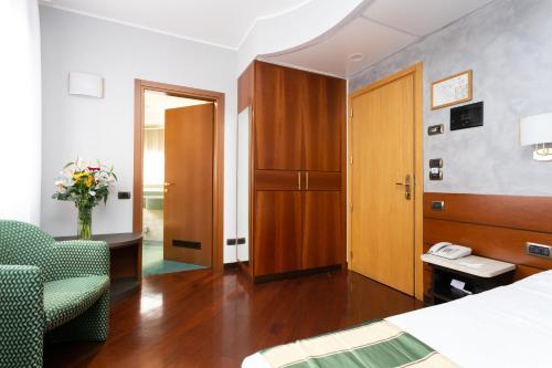 a hotel room with a bed and a chair and a door at Hotel Mirage Sure Hotel Collection by Best Western in Milan