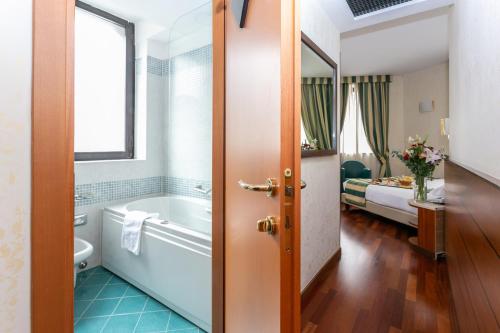 a bathroom with a tub and a bedroom with a bed at Hotel Mirage Sure Hotel Collection by Best Western in Milan