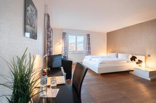 um quarto de hotel com uma cama e uma secretária com um computador em Hotel Alpenhof em Unterbäch
