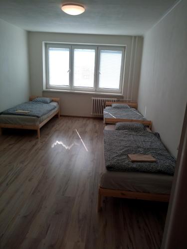 a room with three beds and a window at Apartmány Karviná in Karviná