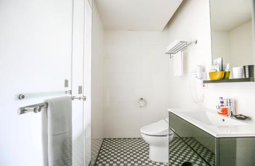 a white bathroom with a toilet and a sink at CityInn Hotel Plus - Taichung Station Branch in Taichung