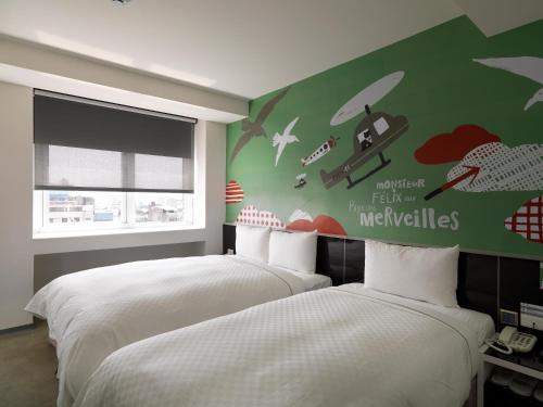 a bedroom with two beds and a green wall at CityInn Hotel Plus - Taichung Station Branch in Taichung