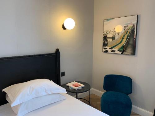 a bedroom with a bed and a blue chair at Hôtel L'orque Bleue in Sète