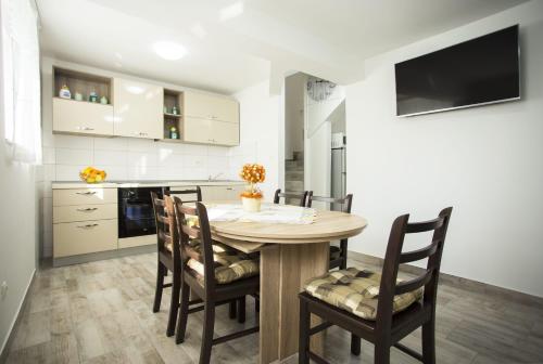 uma cozinha e sala de jantar com uma mesa de madeira e cadeiras em Apartman Leona em Kaštela