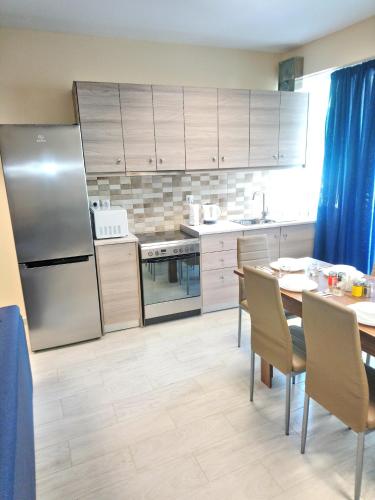a kitchen with a table and a stainless steel refrigerator at JK's GUESTHOUSE KARDAMAINA in Kardamaina