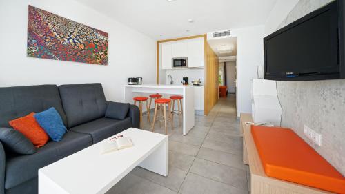 a living room with a couch and a tv at Ura Lara Adults Only in Puerto Rico de Gran Canaria