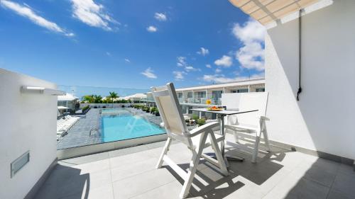a balcony with a table and chairs and a swimming pool at Ura Lara Adults Only in Puerto Rico de Gran Canaria