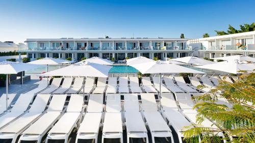 a group of white chairs and umbrellas in front of a building at Ura Lara Adults Only in Puerto Rico de Gran Canaria