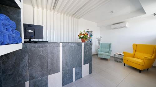 a living room with a yellow chair and a television at Ura Lara Adults Only in Puerto Rico de Gran Canaria