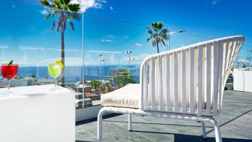 a white chair on a balcony with a table and drinks at Ura Lara Adults Only in Puerto Rico de Gran Canaria