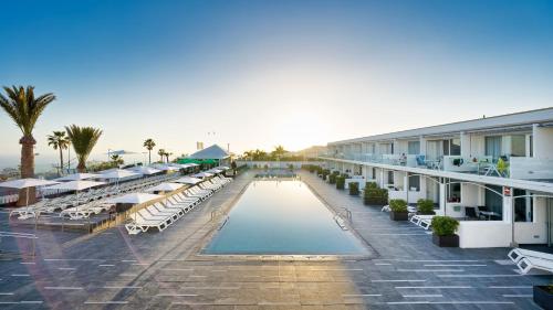 a hotel with a pool and chairs and a resort at Ura Lara Adults Only in Puerto Rico de Gran Canaria