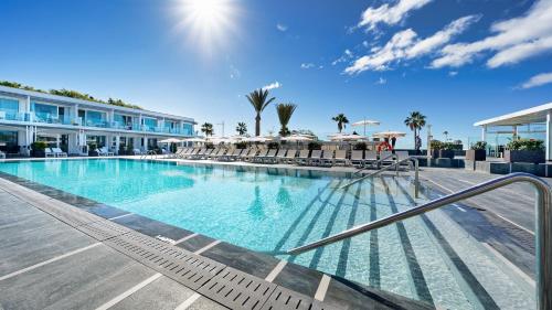 a swimming pool with chairs and umbrellas next to a building at Ura Lara Adults Only in Puerto Rico de Gran Canaria