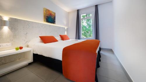 a bedroom with a bed with orange pillows and a window at Ura Lara Adults Only in Puerto Rico de Gran Canaria