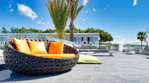 a large basket chair with orange pillows on a patio at Ura Lara Adults Only in Puerto Rico de Gran Canaria