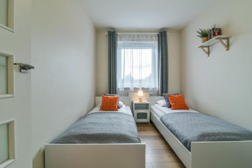 dwa łóżka w pokoju z oknem w obiekcie LTC Apartments Malczewskiego Centrum w Gdańsku