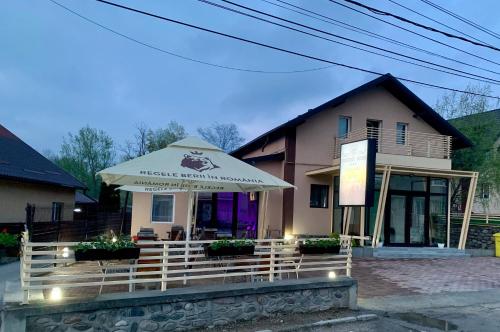 a restaurant with an umbrella in front of a building at Pensiunea Prestige House in Curtea de Argeş