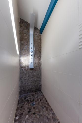 a shower in a bathroom with a stone floor at Alpinias Bed and Breakfast in Marseille