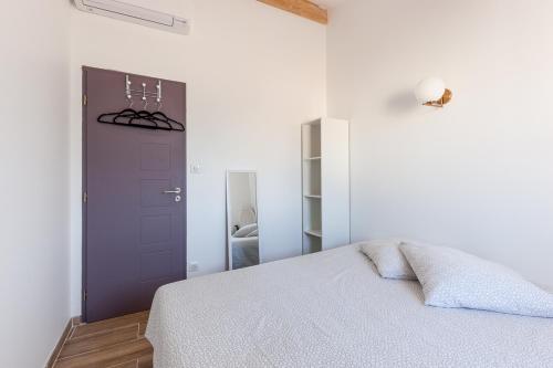 um quarto branco com uma cama e uma porta roxa em Alpinias Bed and Breakfast em Marselha