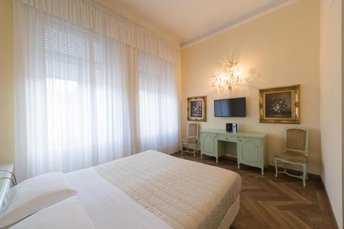 a bedroom with a bed and a desk and a television at Grand Hotel Liberty in Riva del Garda