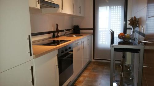 La Penilla的住宿－Cabárceno，厨房配有白色橱柜、水槽和炉灶。