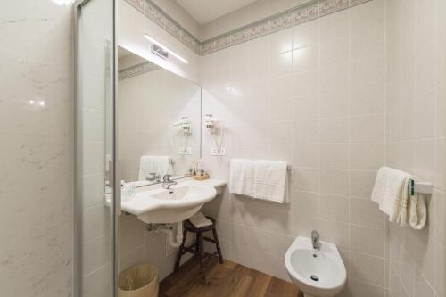 a white bathroom with a sink and a mirror at Grand Hotel Liberty in Riva del Garda