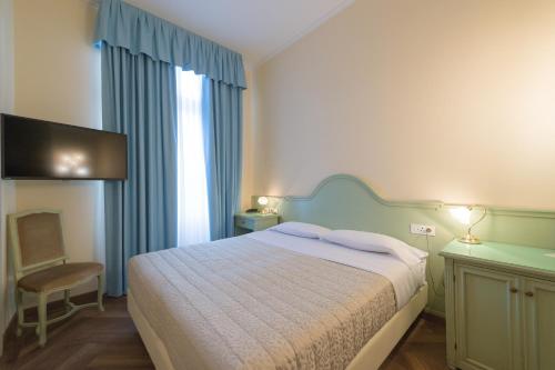 a bedroom with a bed and a chair and a window at Grand Hotel Liberty in Riva del Garda