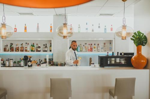 a bartender behind the bar at a restaurant at Hotel Alay - Adults Only Recommended in Benalmádena