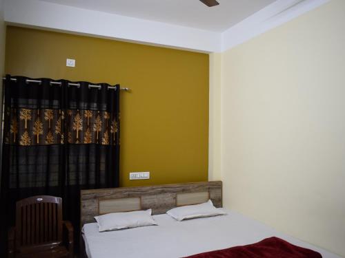 a bedroom with a bed and a yellow wall at Jupiter Lodge in Siliguri