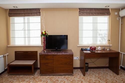 a living room with a flat screen tv and two windows at Soluxe Hotel Almaty in Almaty