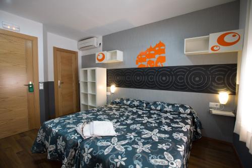 a bedroom with a bed with a blue and white bedspread at Hostal Gaudi Cuenca in Cuenca
