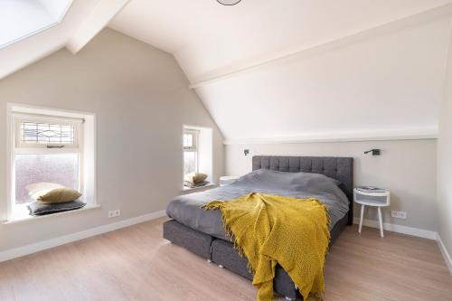 a bedroom with a bed with a yellow blanket on it at Boerderijwoning in Serooskerke