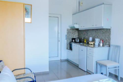 a kitchen with white cabinets and a table and a chair at Seaview Studio in Gázion